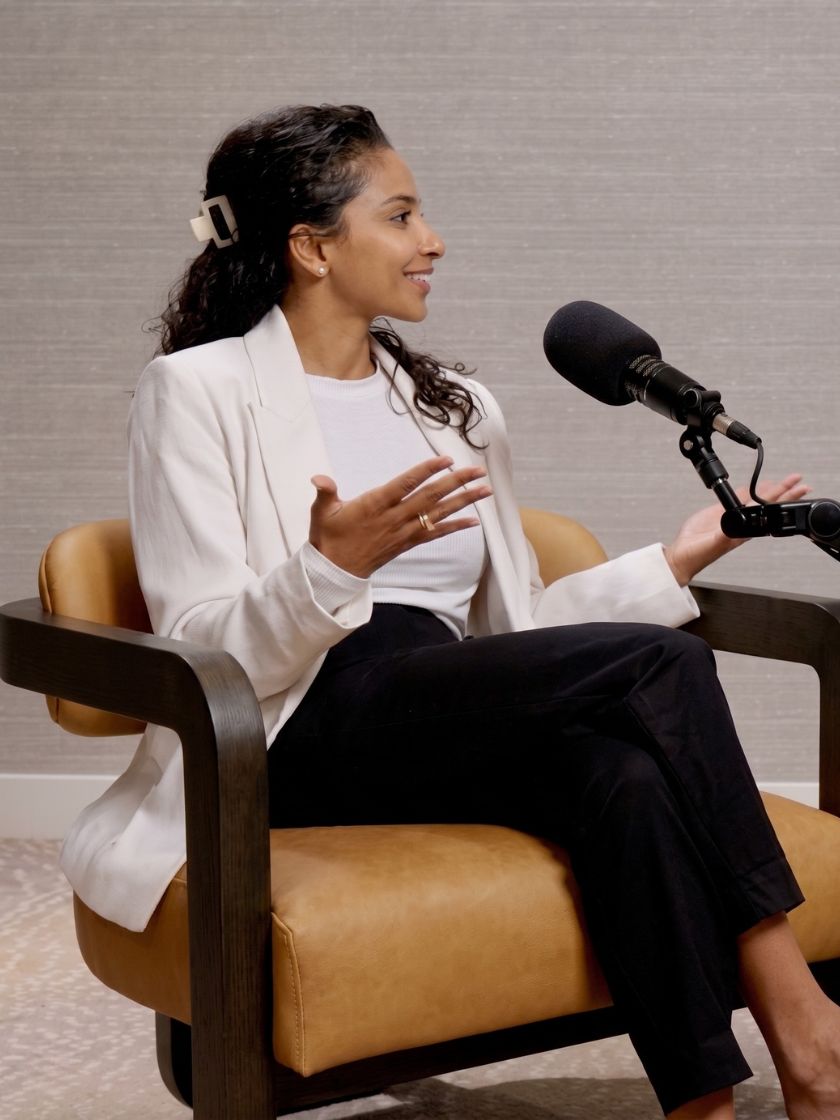Dr. Christina Paul speaking on a podcast set, seated in a leather chair in front of a microphone